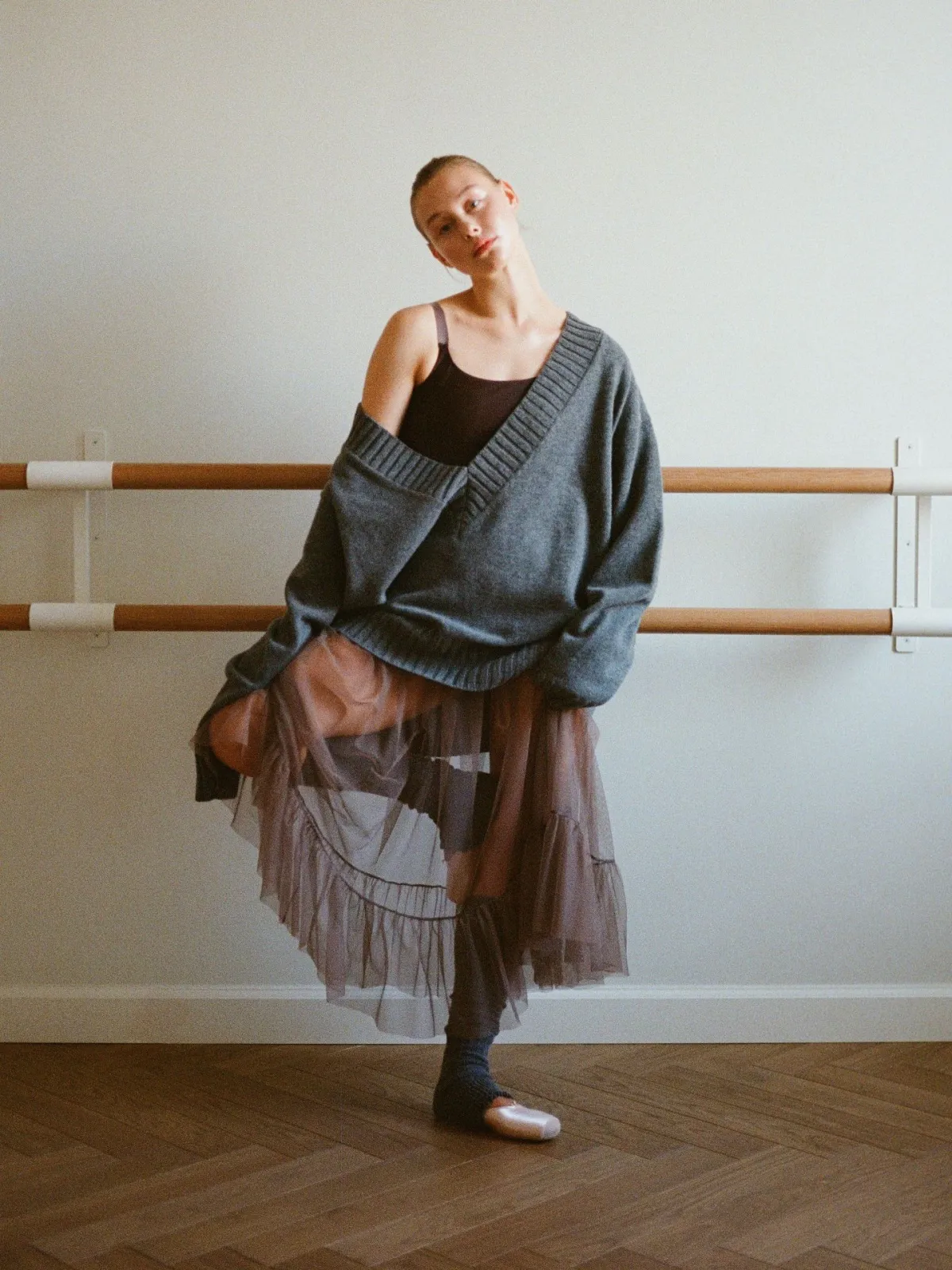 Balletcore aesthetic — Directly showcases a ballet studio setting with a dancer in a wrap cardigan, tulle skirt, and ballet flats, embodying the core aesthetic.
