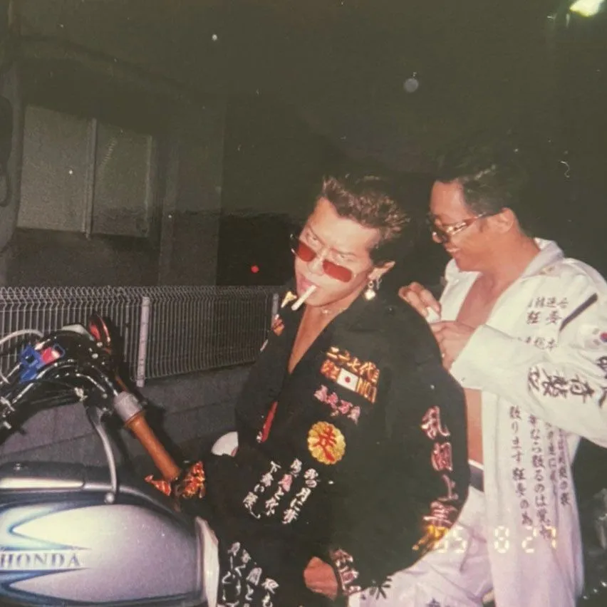 Bosozoku aesthetic — The vintage feel, pompadour hairstyle, embroidered tokko-fuku style jacket, and the presence of a motorcycle strongly align with the description.