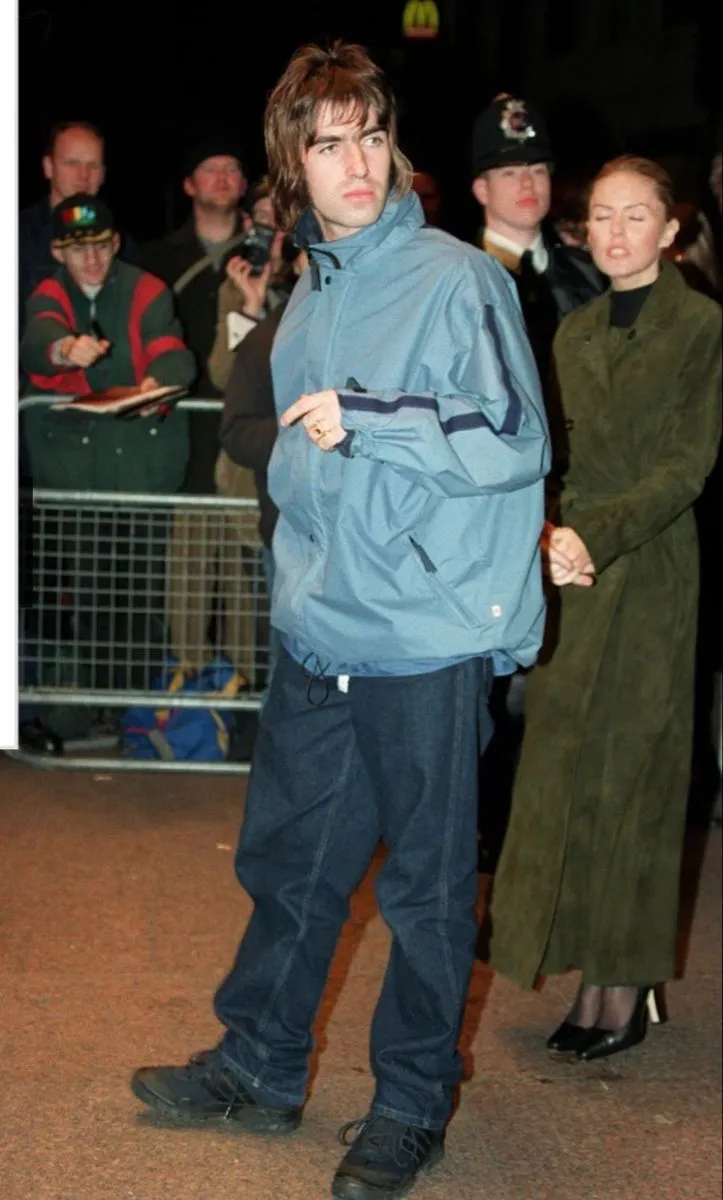 Britpop aesthetic — Liam Gallagher in a blue jacket and dark jeans, a quintessential Britpop look.