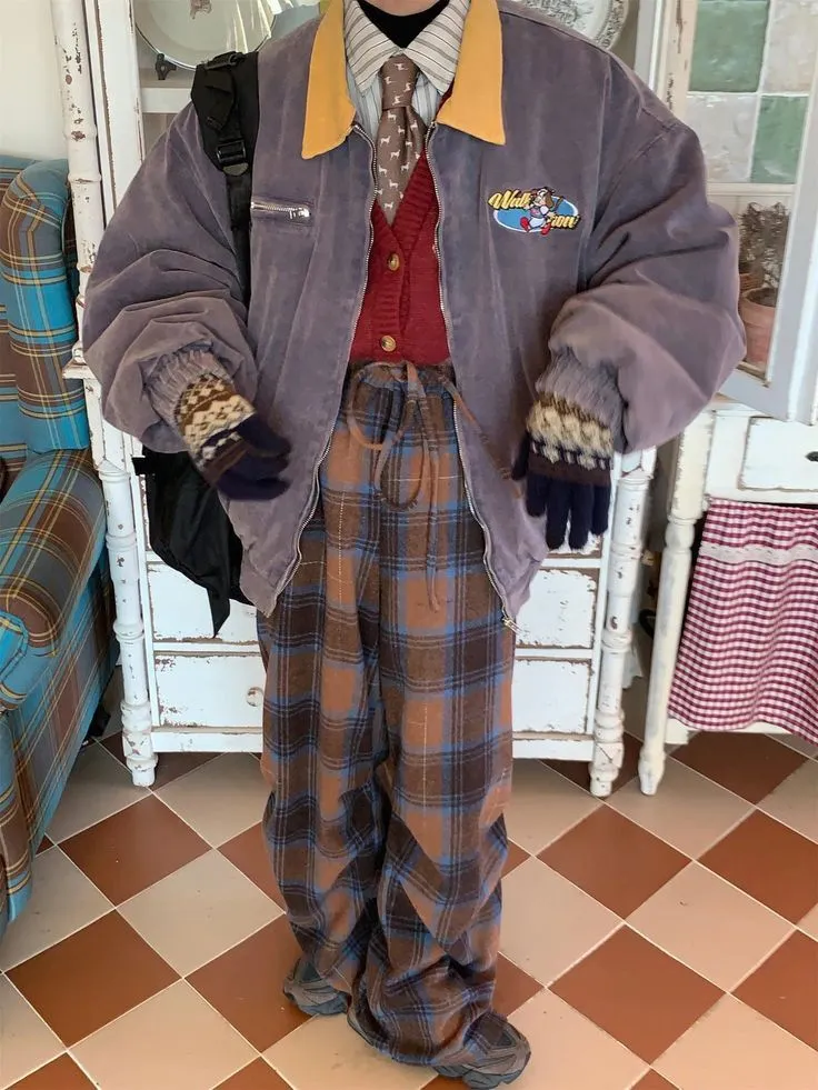 Chaotic Academia aesthetic — The layered knitwear (cardigan under a zip-up jacket), plaid trousers, and slightly mismatched accessories strongly capture the 'messy notes, paint-splattered cardigans, cluttered desks' vibe of Chaotic Academia.