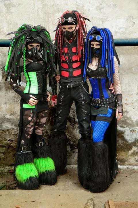 Cybergoth aesthetic — This group shot exemplifies Cybergoth with multiple individuals sporting cyberlox, gas masks, neon accents (green and blue), PVC, and platform boots.