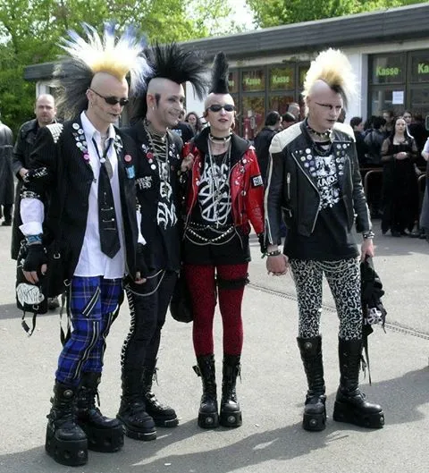 Deathrock aesthetic — The combination of extreme backcombed hair, ripped fishnets, deconstructed band tees, leather jackets, and platform boots strongly aligns with the visual signature and signature garments of Deathrock.