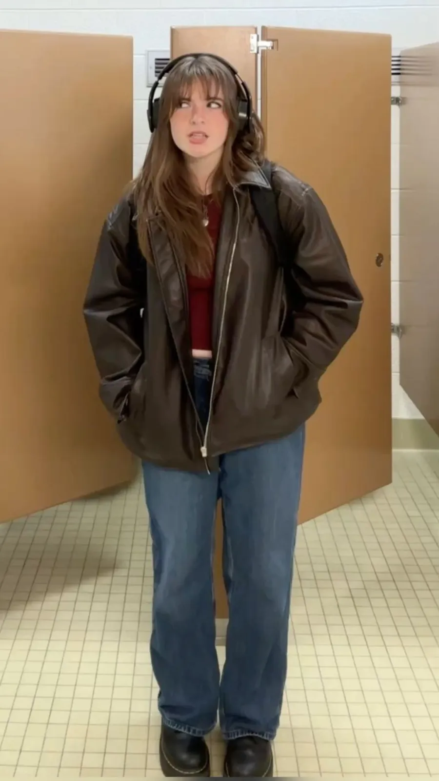 Downtown Girl aesthetic — Oversized leather jacket, baggy jeans, and headphones around the neck directly reference the 90s grunge and art-student chic elements of the description.