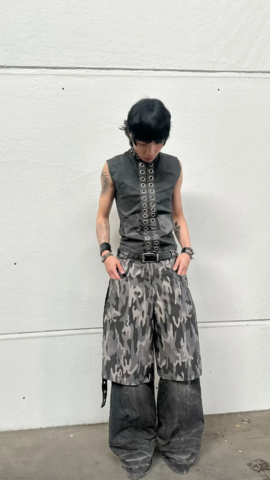 Draincore aesthetic — The excessive metal hardware on the vest and belt, layered chains, baggy cargo pants, and overall industrial rave-wear vibe strongly align with the description's emphasis on hardware and rave-wear spectrum.