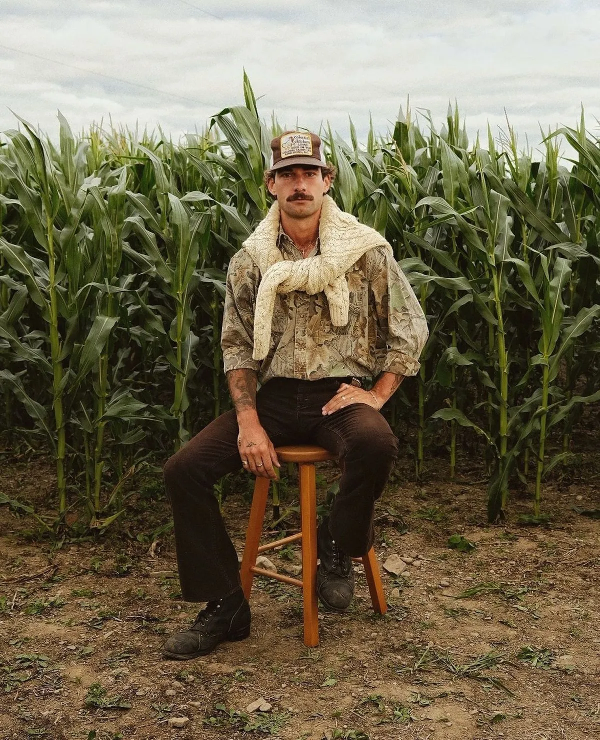 Farmcore aesthetic — The double-knee work pants, plaid shirt, trucker cap, and work boots clearly align with Farmcore's function-first, agricultural workwear aesthetic.