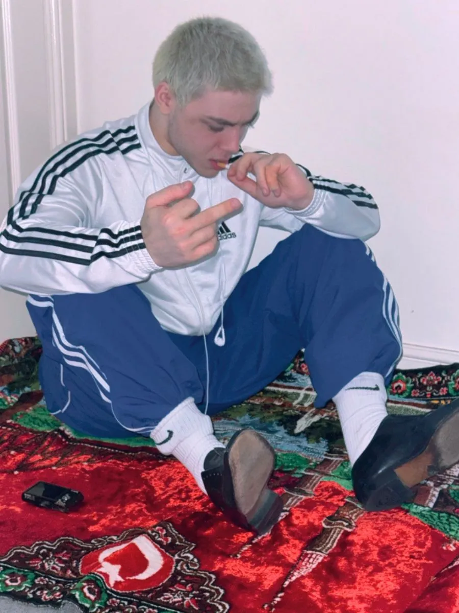 Gopnik aesthetic — Classic Adidas tracksuit, pointed loafers, and the slav squat pose, capturing the core visual signature and mood.