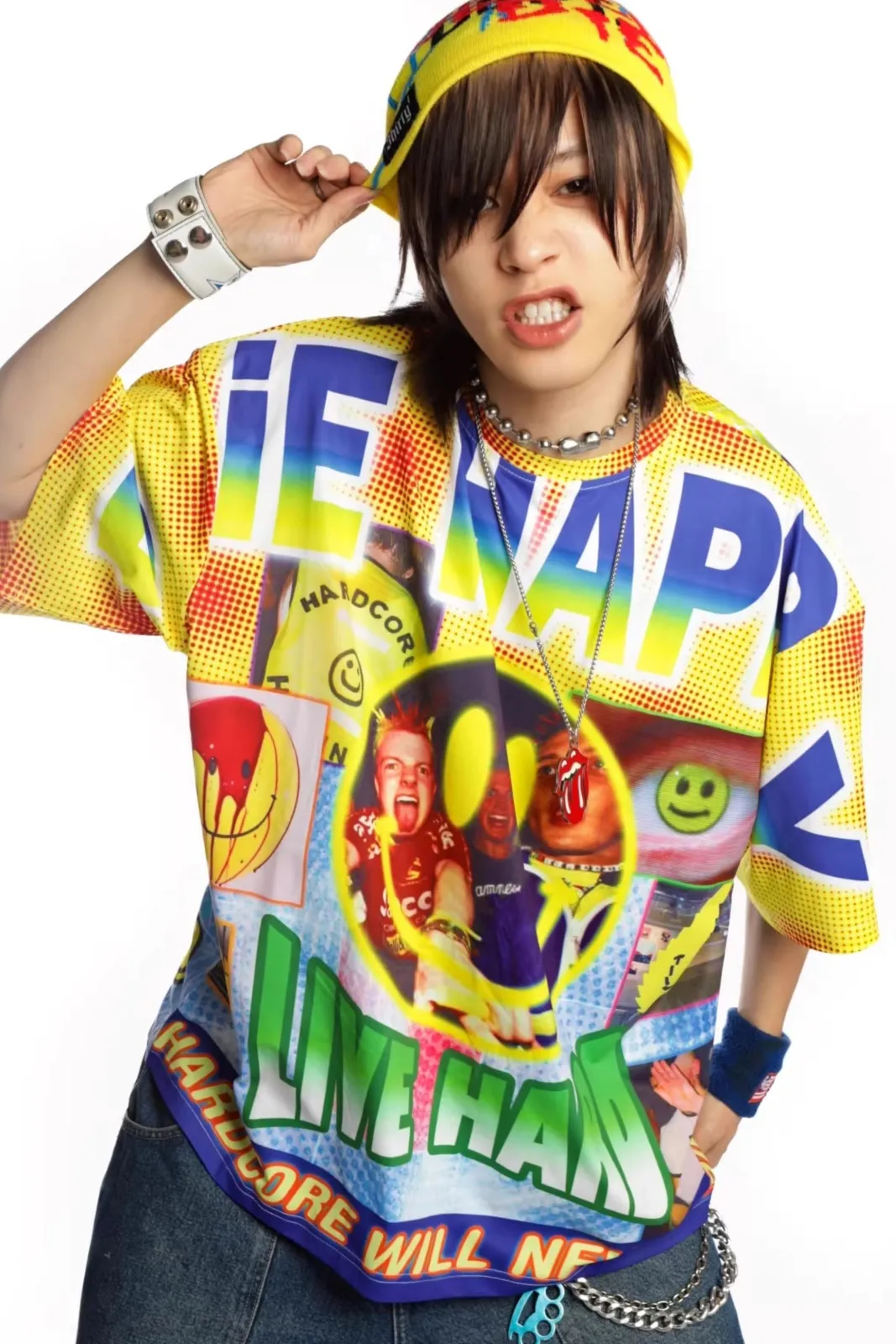 Happy Hardcore aesthetic — The all-over print t-shirt featuring smiley faces, 'Happy Hardcore' text, and images of ravers directly references the genre's name and visual motifs, along with the yellow bucket hat and denim jeans, strongly aligning with the description.