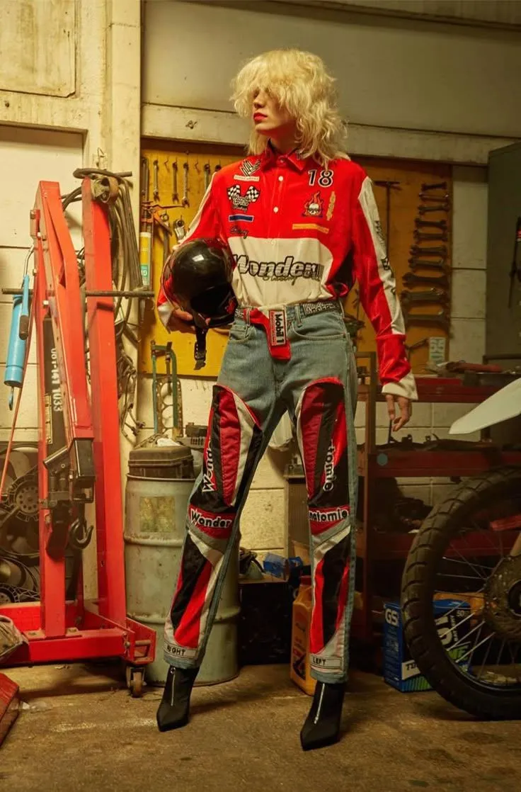 Hot Rod aesthetic — The racing-inspired jumpsuit with patches and the helmet evoke the car-racing pit lane aspect of the Hot Rod aesthetic.