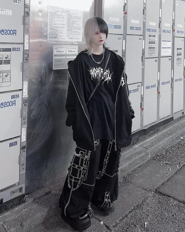 Jirai Danshi aesthetic — The layered chains, chokers, ear cuffs, dyed black hair (split dye), oversized hoodie, and chunky platform shoes are all signature elements.