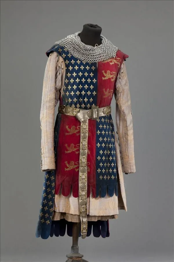 Medieval aesthetic — This image is a direct representation of medieval knightly attire, featuring a surcoat with heraldic symbols, chainmail, and a period-appropriate belt, aligning perfectly with the description's signature garments and era.