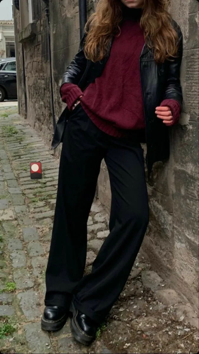 Messy French Girl aesthetic — The leather jacket over a burgundy sweater with black trousers and chunky boots perfectly captures the 'darker rock-and-roll sensibility' and the mix of basic pieces with a tougher edge, fitting the nighttime mutation.