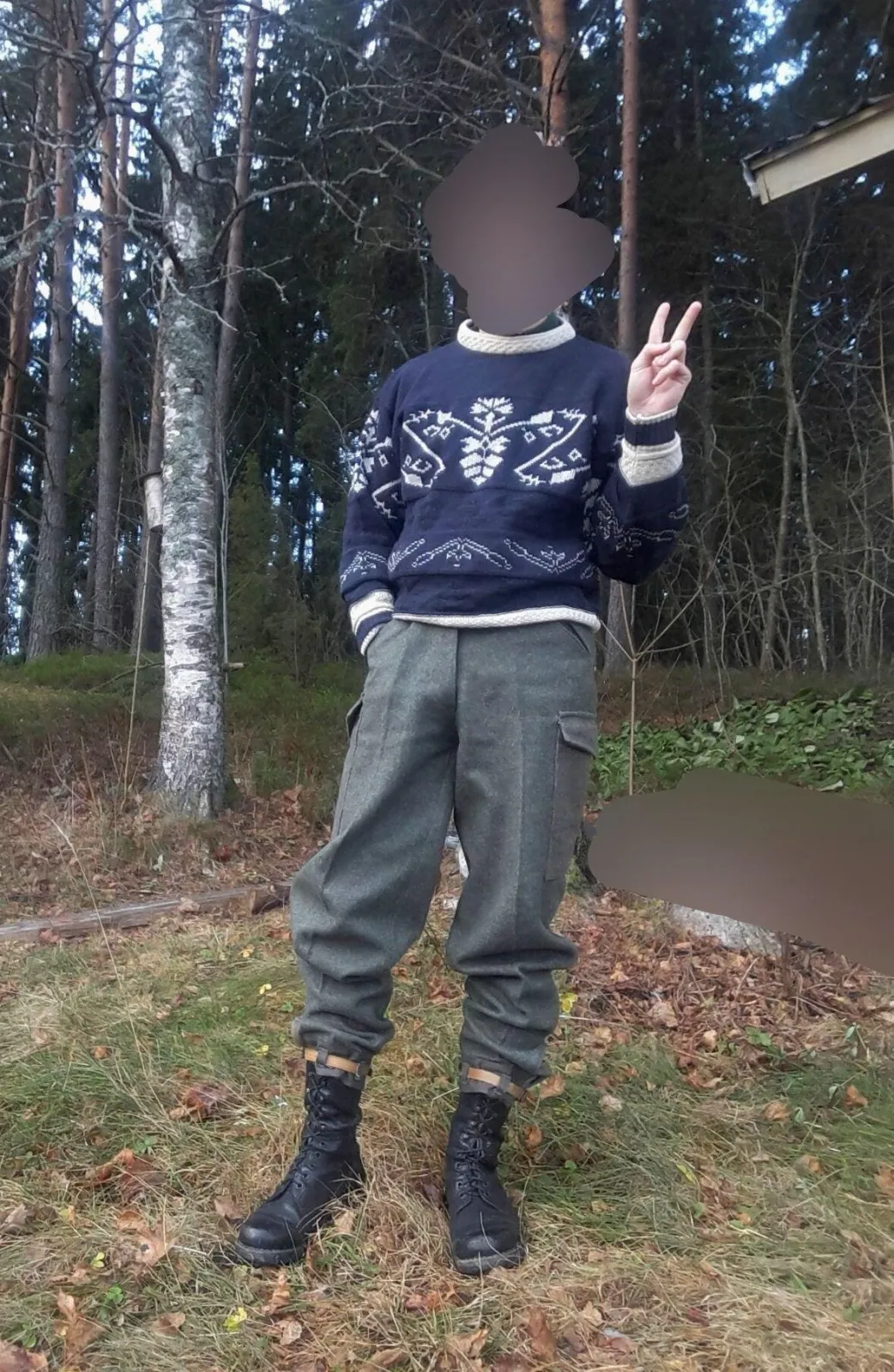 Neofolk aesthetic — The hand-knitted wool jumper with folk patterns, military surplus-style trousers, and sturdy boots perfectly capture the described visual signature and rural folk elements.