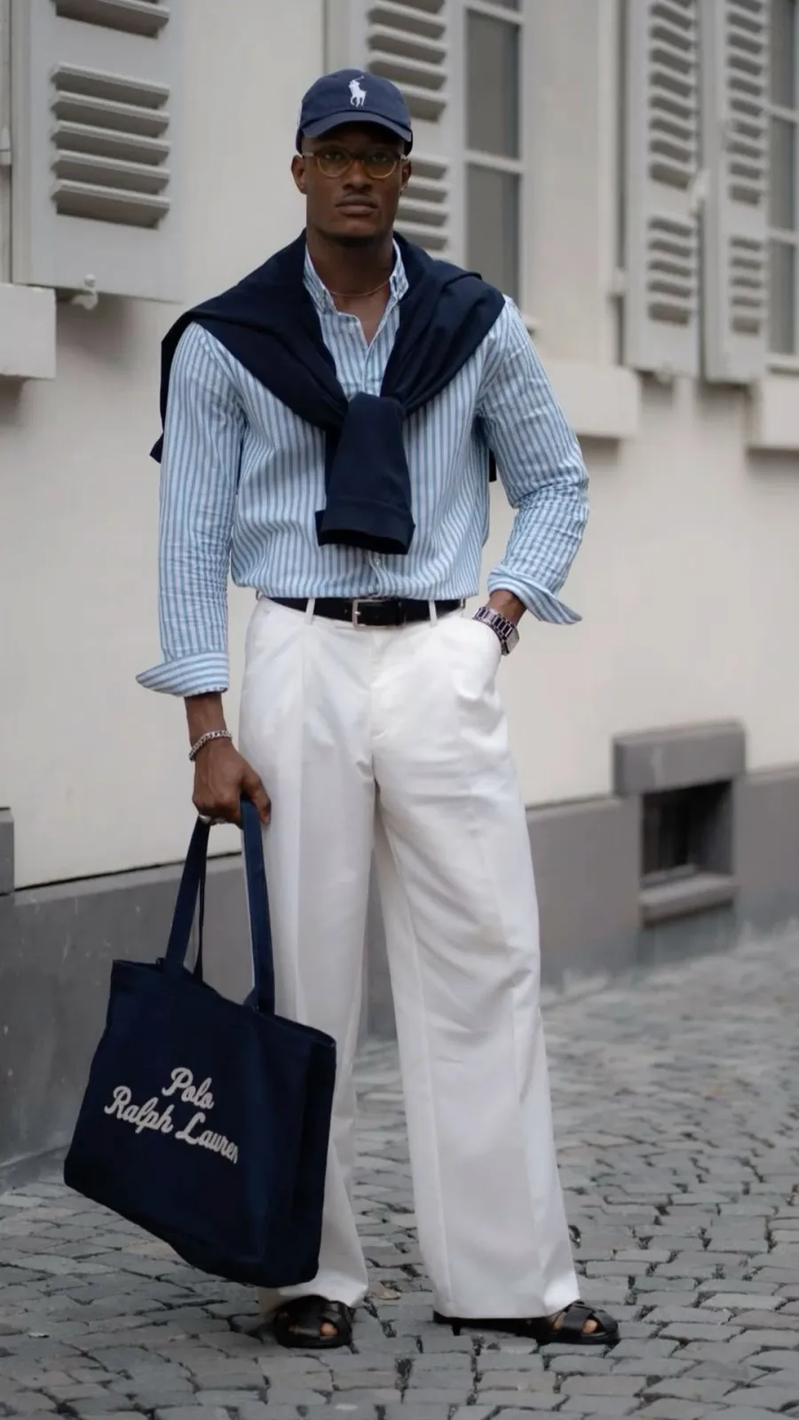 Old Money aesthetic — The navy blazer tied over the shoulders, striped button-down, and Polo Ralph Lauren tote bag are direct references to the description's visual signature and canonical brands.