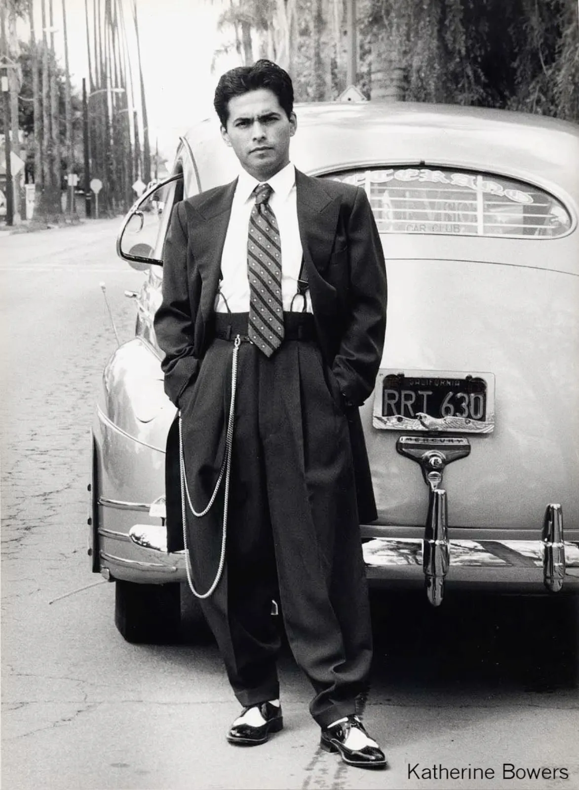 Pachuco aesthetic — The classic zoot suit, high-waisted pegged trousers, suspenders, watch chain, and two-tone shoes are all definitive Pachuco visual signatures.