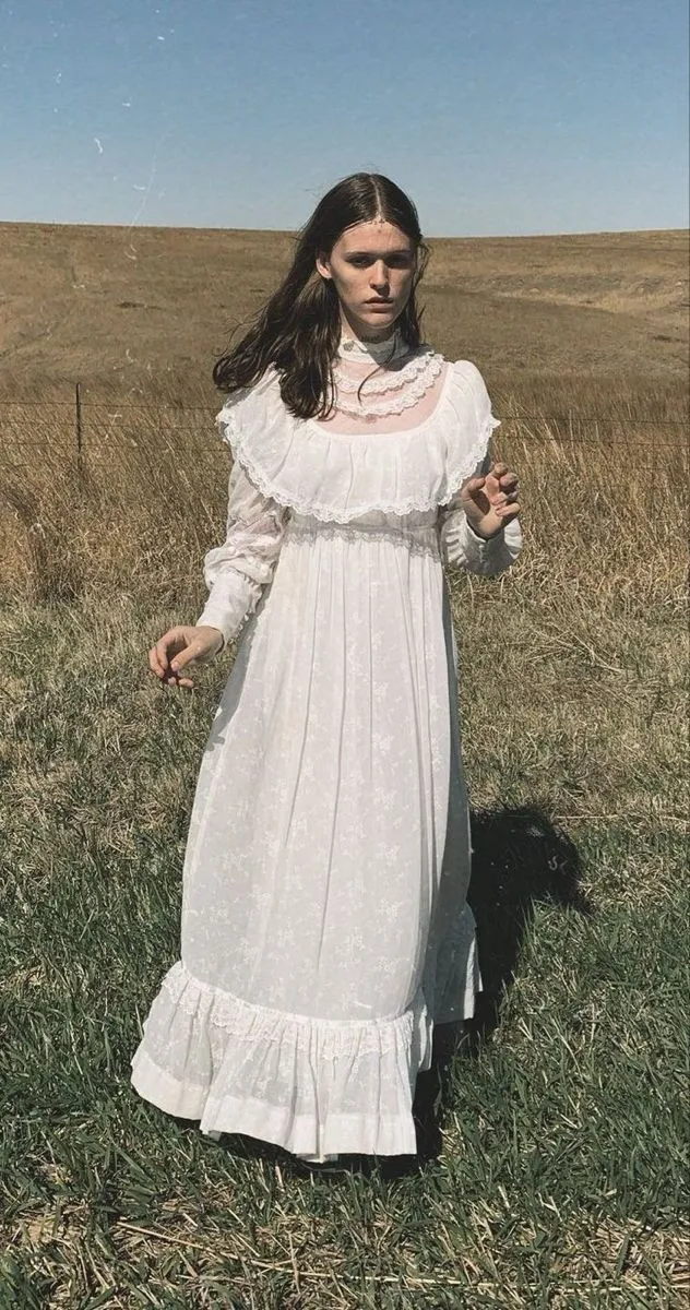 Preacher's Daughter aesthetic — The long white prairie dress with lace details and the outdoor setting strongly align with the aesthetic's signature garments and Southern Gothic atmosphere.