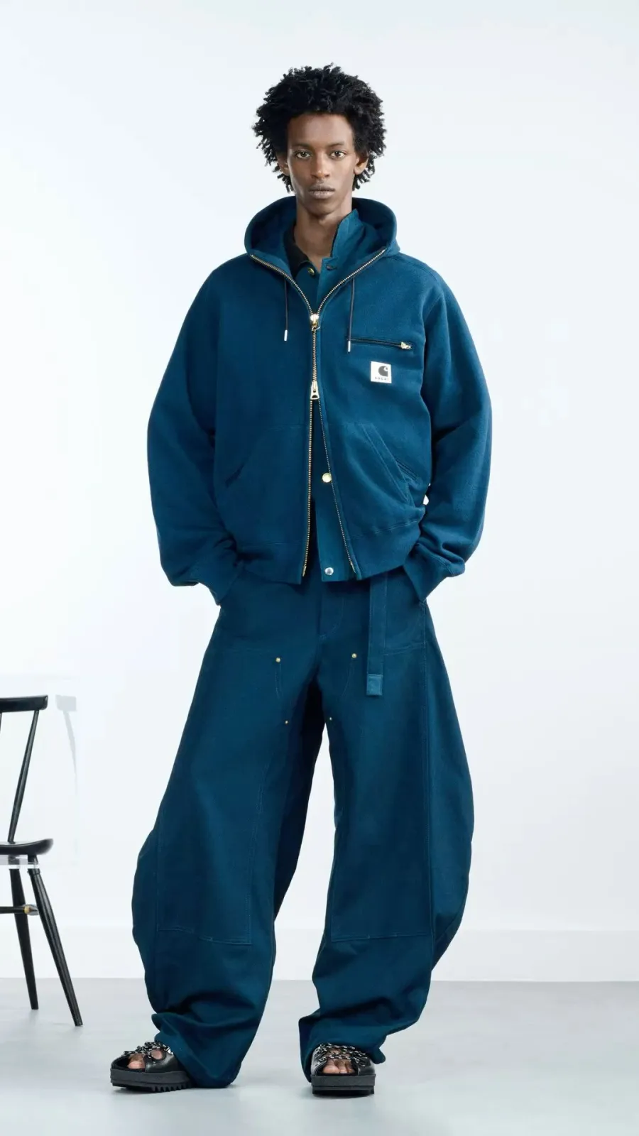 Streetwear aesthetic — The full Carhartt-style outfit with a zip-up hoodie and extremely baggy pants is a direct nod to the workwear influence and silhouette central to streetwear.
