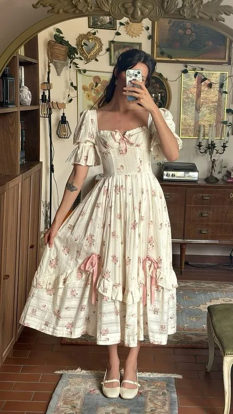Tradcath Coquette aesthetic — The floral prairie dress with lace trim, pink bows, and puff sleeves strongly evokes the 'messy yet sweet' femininity and signature garments described, fitting the mid-2020s era.