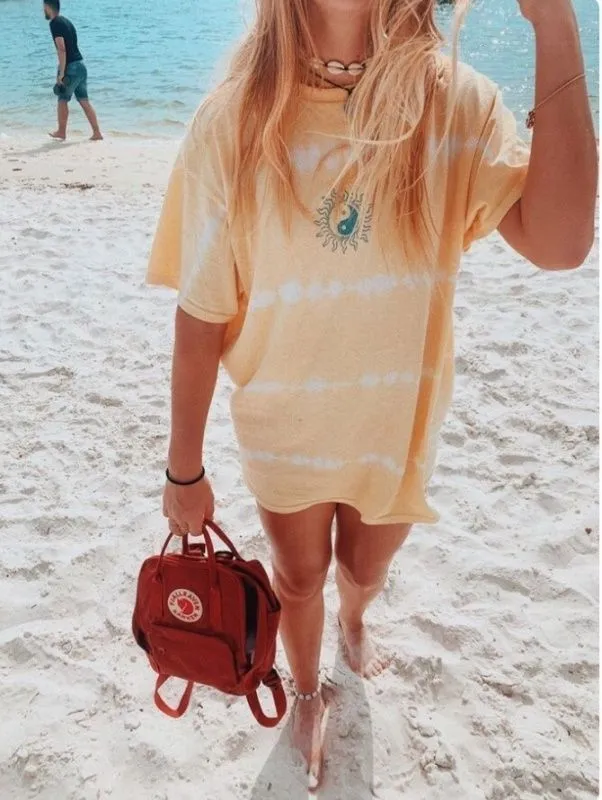 VSCO Girl aesthetic — Oversized tie-dye tee, Fjällräven Kånken backpack, and shell choker are all specific VSCO Girl signifiers.