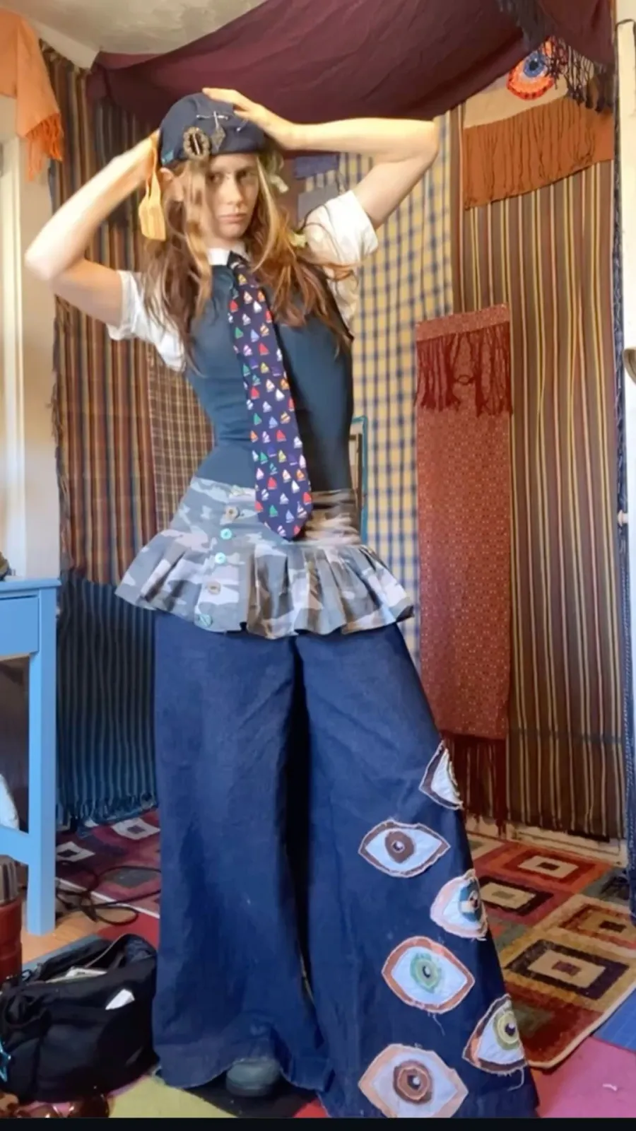 Weirdcore aesthetic — The combination of ill-fitting proportions, DIY-strange styling (eye patches on pants), and clashing patterns strongly aligns with the Weirdcore aesthetic.